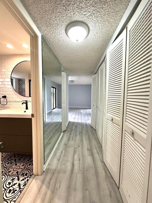 601 Ives Dairy Rd Unit 401-8, Miami, FL 33179 - corridor featuring light wood finished floors, a textured ceiling, a sink, and baseboards
