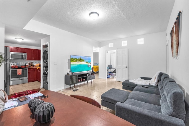 5271 SW 8th St Unit 311, Miami, FL 33134 - living room featuring stacked washing machine and dryer, light tile patterned floors, a textured ceiling, and baseboards