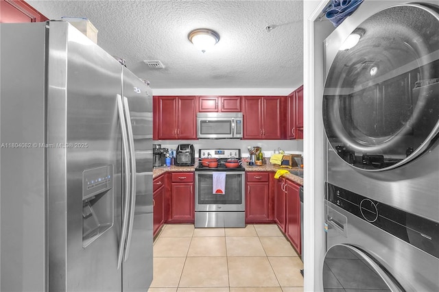 5271 SW 8th St Unit 311, Miami, FL 33134 - kitchen with stainless steel appliances, reddish brown cabinets, estacked washer and dryer, a textured ceiling, and light tile patterned floors