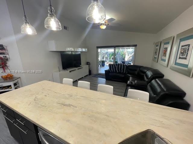 17201 SW 143rd Ct, Miami, FL 33177 - kitchen featuring vaulted ceiling, open floor plan, a ceiling fan, hanging light fixtures, and wood finished floors