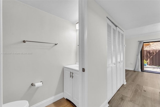 bathroom with toilet, baseboards, wood finished floors, and vanity