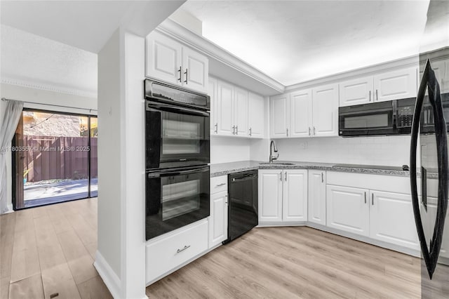 kitchen with black appliances, a sink, light wood finished floors, white cabinetry, and a textured ceiling