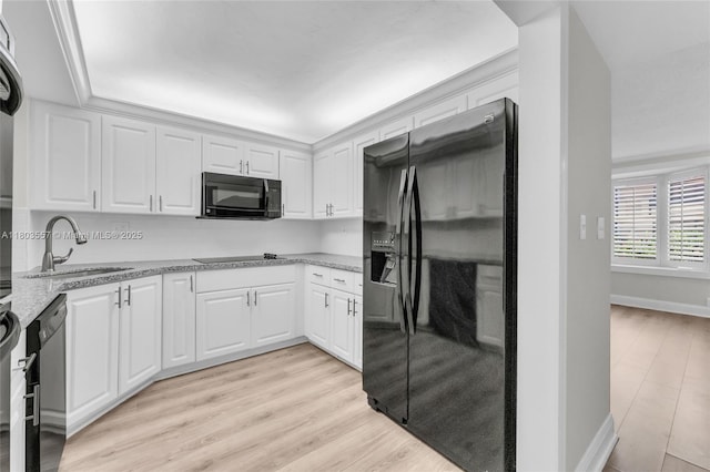 kitchen featuring black appliances, a sink, white cabinetry, and light wood finished floors