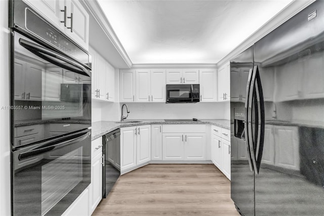 kitchen with black appliances, white cabinetry, light wood-style flooring, and light stone countertops