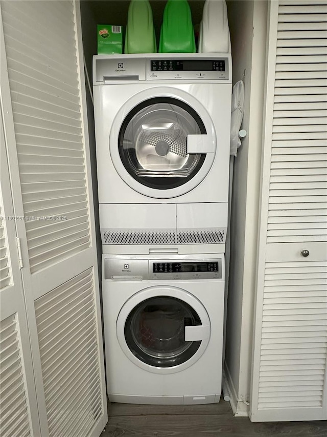 laundry room featuring stacked washer / dryer and wood finished floors