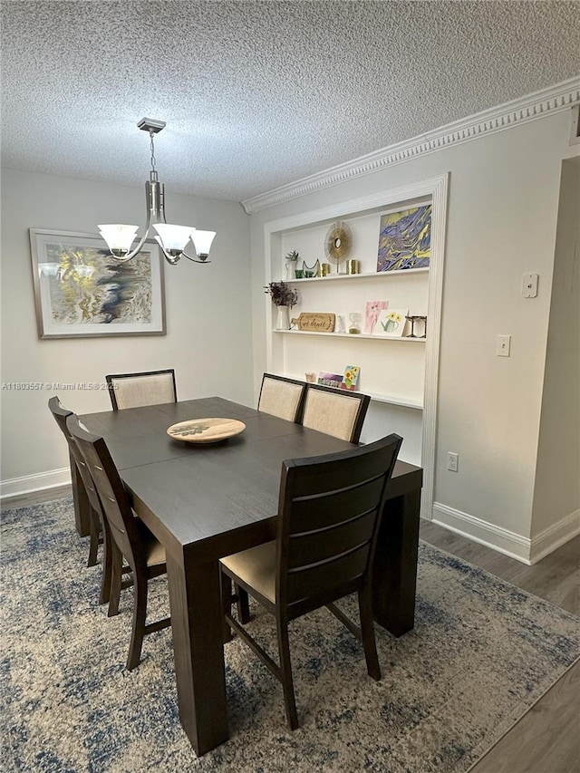 dining space featuring a chandelier, wood finished floors, a textured ceiling, and baseboards
