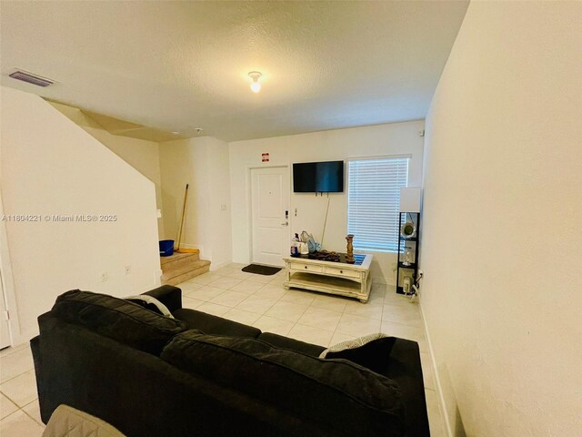 448 NE 4th St, Florida City, FL 33034 - living area featuring light tile patterned flooring, stairway, and a textured ceiling