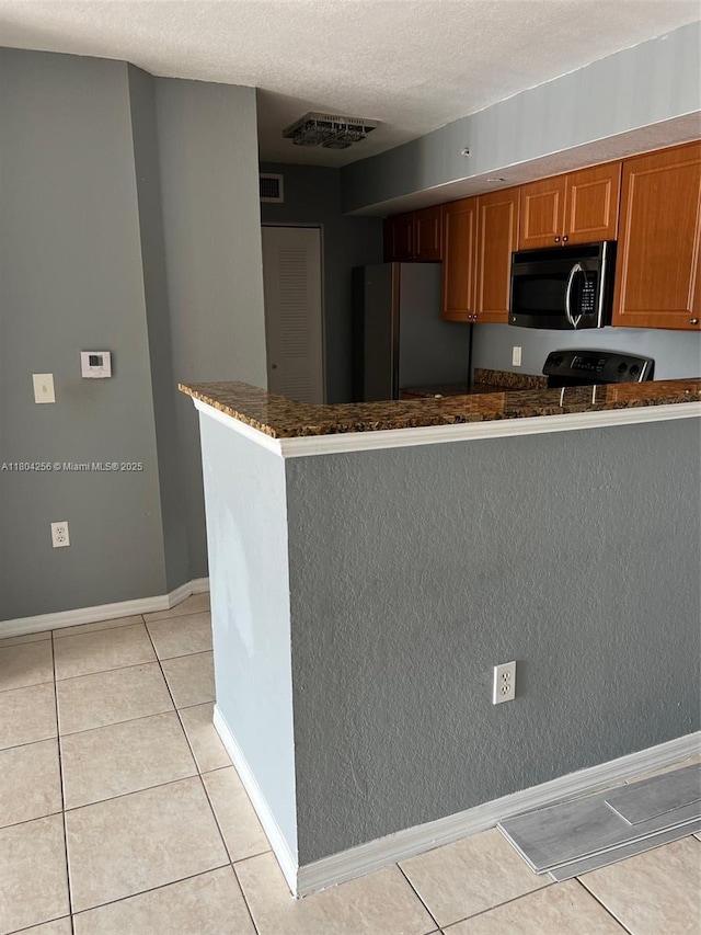 13780 NE 3rd Ct Unit 207, North Miami, FL 33161 - kitchen with appliances with stainless steel finishes, light tile patterned floors, a textured ceiling, a peninsula, and brown cabinetry