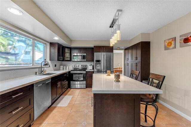 9465 SW 146th Ct, Miami, FL 33186 - kitchen featuring appliances with stainless steel finishes, a sink, a breakfast bar area, a center island, and light tile patterned flooring