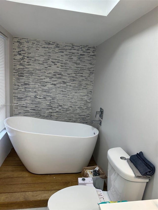 685 NE 206th Ter, Miami, FL 33179 - full bathroom with toilet, a freestanding bath, wood finished floors, and an accent wall