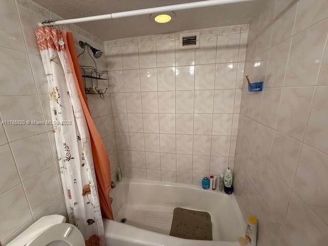 801 Three Islands Blvd Unit 302, Hallandale Beach, FL 33009 - bathroom featuring shower / bathtub combination with curtain, toilet, and tile walls