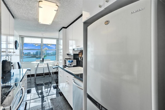 301 174th St Unit 1503, Sunny Isles Beach, FL 33160 - kitchen with appliances with stainless steel finishes, white cabinetry, a textured ceiling, dark countertops, and a sink