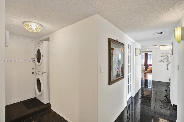 301 174th St Unit 1503, Sunny Isles Beach, FL 33160 - laundry area featuring stacked washing machine and dryer, a textured ceiling, and baseboards