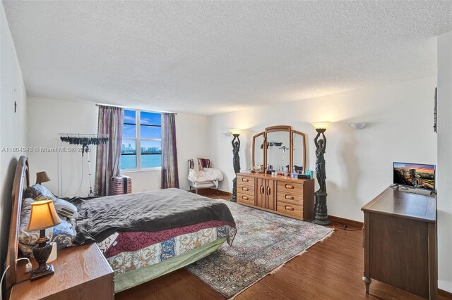 301 174th St Unit 1503, Sunny Isles Beach, FL 33160 - bedroom with a textured ceiling, wood finished floors, and baseboards