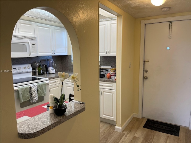 2911 N Pine Island Rd Unit 311, Sunrise, FL 33322 - kitchen with white appliances, light wood-style flooring, white cabinets, arched walkways, and dark countertops