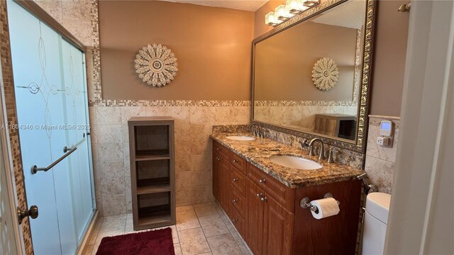 14620 SW 151st Ter, Miami, FL 33186 - bathroom with tile walls, double vanity, a wainscoted wall, toilet, and a shower with shower door