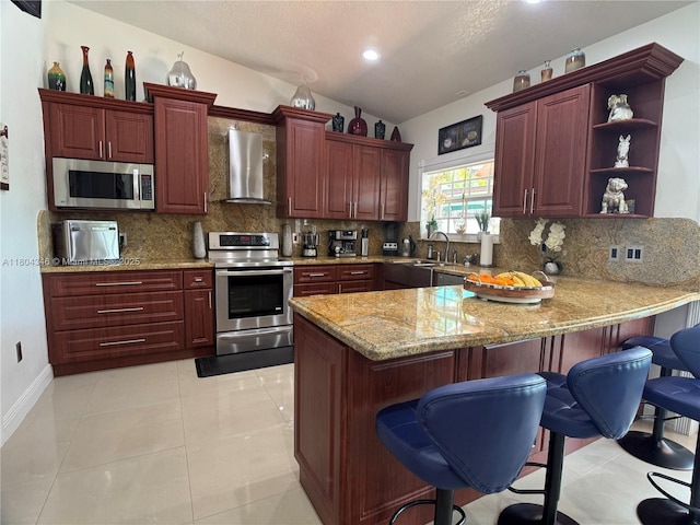 14620 SW 151st Ter, Miami, FL 33186 - kitchen with appliances with stainless steel finishes, wall chimney range hood, a peninsula, reddish brown cabinets, and lofted ceiling