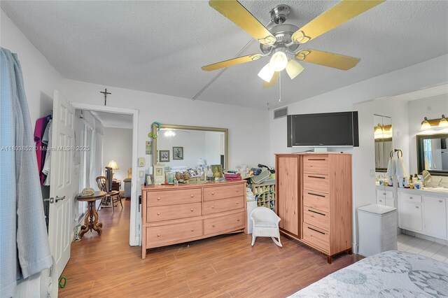 9781 Sunrise Lakes Blvd Unit 202, Sunrise, FL 33322 - bedroom featuring light wood-style flooring, a textured ceiling, ceiling fan, and ensuite bath