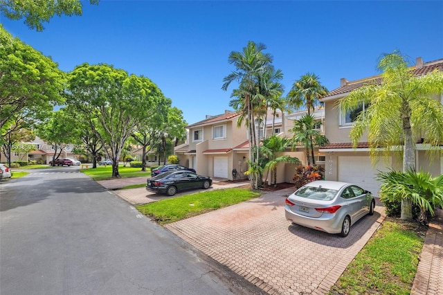 townhome / multi-family property with decorative driveway, an attached garage, stucco siding, and a residential view