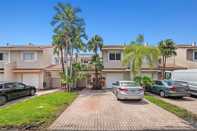 multi unit property featuring driveway, a garage, and stucco siding