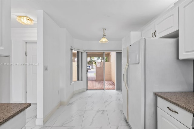 kitchen featuring light marble finish floors, white fridge with ice dispenser, white cabinetry, dark stone counters, and baseboards