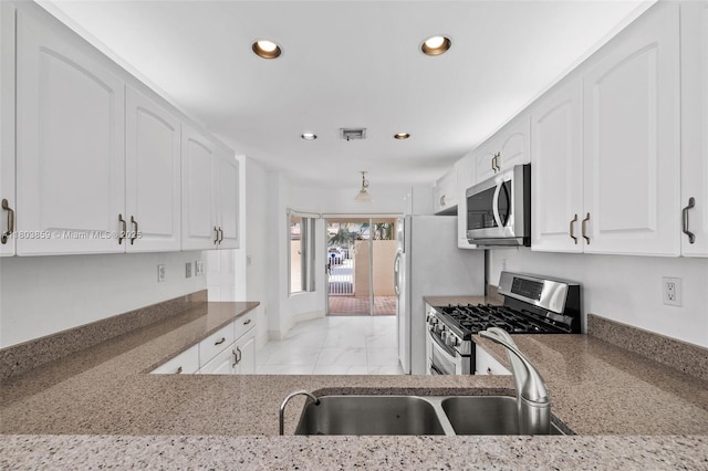 kitchen featuring appliances with stainless steel finishes, recessed lighting, white cabinetry, dark stone counters, and light marble finish flooring
