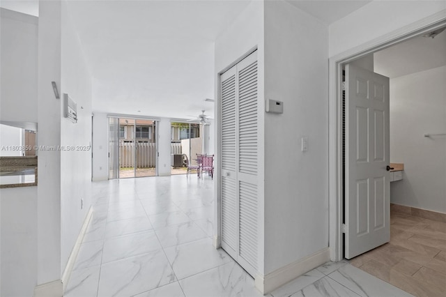 hallway featuring baseboards and light marble finish floors