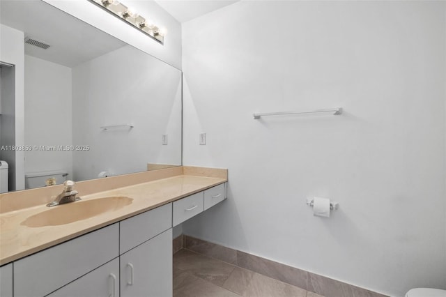 bathroom featuring toilet, vanity, tile patterned flooring, and baseboards