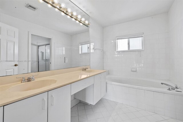 full bathroom with a shower with door, tiled bath, plenty of natural light, and double vanity