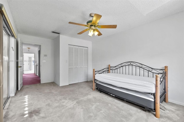 bedroom featuring carpet, a closet, a textured ceiling, baseboards, and ceiling fan