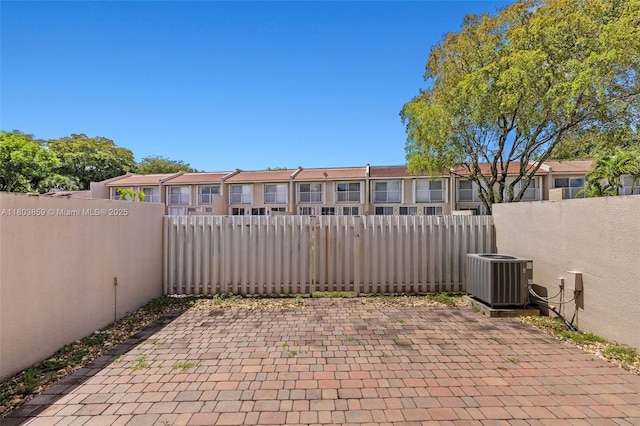 view of patio with central air condition unit, fence, and a residential view