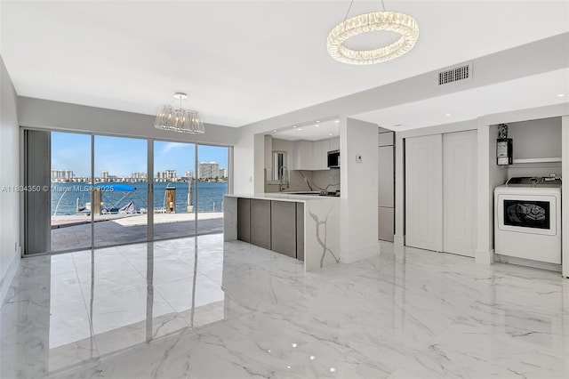 2807 NE 164th St Unit 2, North Miami Beach, FL 33160 - kitchen featuring modern cabinets, washer / dryer, light marble finish flooring, a chandelier, and stainless steel microwave