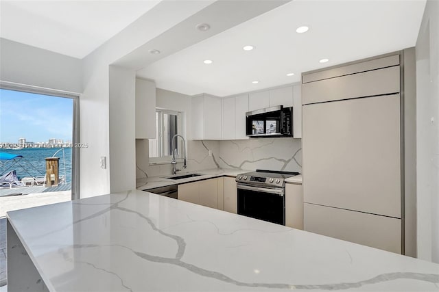 2807 NE 164th St Unit 2, North Miami Beach, FL 33160 - kitchen featuring stainless steel appliances, a sink, modern cabinets, backsplash, and light stone countertops