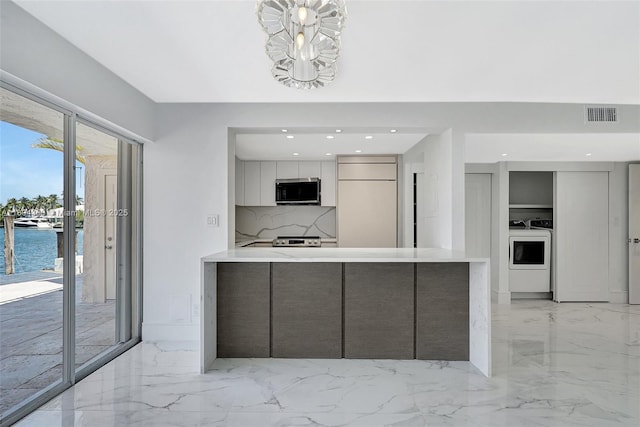 2807 NE 164th St Unit 2, North Miami Beach, FL 33160 - kitchen featuring modern cabinets, stainless steel appliances, light marble finish floors, white cabinets, and washer and dryer