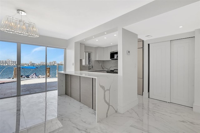 2807 NE 164th St Unit 2, North Miami Beach, FL 33160 - kitchen with stainless steel microwave, light marble finish flooring, a chandelier, modern cabinets, and a water view