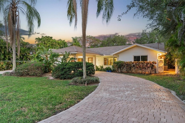 ranch-style house with decorative driveway, stucco siding, and a front lawn