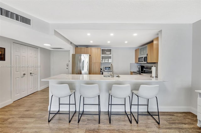800 SE 20th Ave Unit 303, Deerfield Beach, FL 33441 - kitchen featuring appliances with stainless steel finishes, a peninsula, a kitchen breakfast bar, light countertops, and recessed lighting