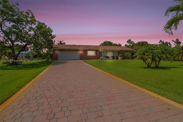 12411 SW 12th St, Davie, FL 33325 - ranch-style house featuring decorative driveway, an attached garage, a yard, a tile roof, and brick siding