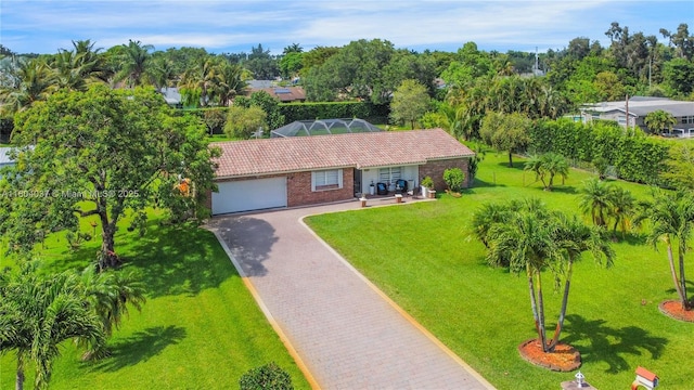 12411 SW 12th St, Davie, FL 33325 - view of front facade with an attached garage, brick siding, driveway, a front yard, and view of wooded area