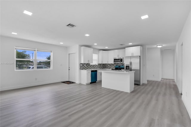 8330 NW 35th Pl, Miami, FL 33147 - kitchen with stainless steel appliances, open floor plan, baseboards, backsplash, and white cabinets