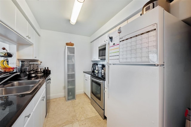 2475 Brickell Ave Unit 1805, Miami, FL 33129 - kitchen featuring stainless steel appliances, a sink, dark countertops, white cabinets, and baseboards