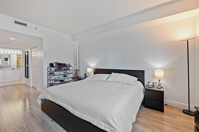 2475 Brickell Ave Unit 1805, Miami, FL 33129 - bedroom featuring light wood finished floors, baseboards, connected bathroom, and a textured ceiling