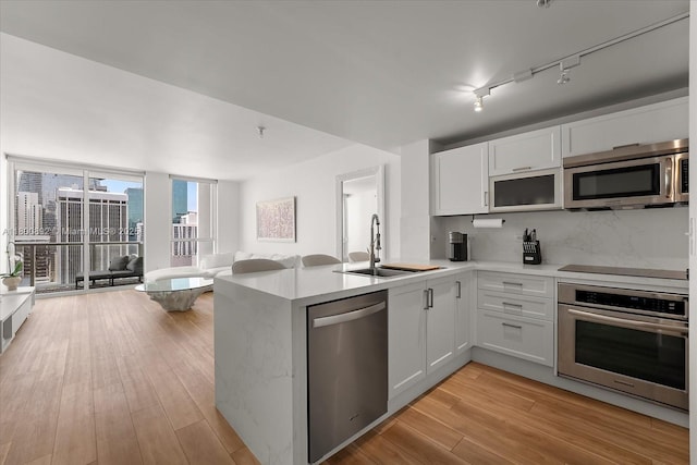 244 Biscayne Blvd Unit 2407, Miami, FL 33132 - kitchen featuring appliances with stainless steel finishes, open floor plan, a peninsula, light countertops, and light wood-type flooring