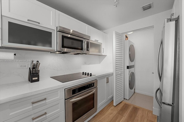 244 Biscayne Blvd Unit 2407, Miami, FL 33132 - kitchen featuring appliances with stainless steel finishes, stacked washing machine and dryer, white cabinetry, decorative backsplash, and light countertops