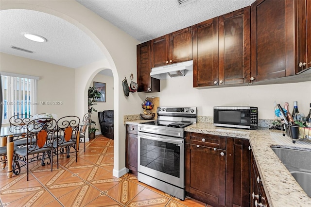 30701 SW 156th Ave, Homestead, FL 33033 - kitchen featuring stainless steel electric range oven, under cabinet range hood, arched walkways, a textured ceiling, and light tile patterned flooring