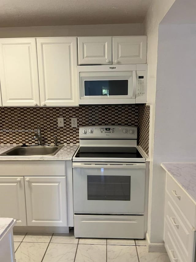 927 NE 199th St Unit 102, Miami, FL 33179 - kitchen with white appliances, a sink, light marble finish floors, and white cabinets