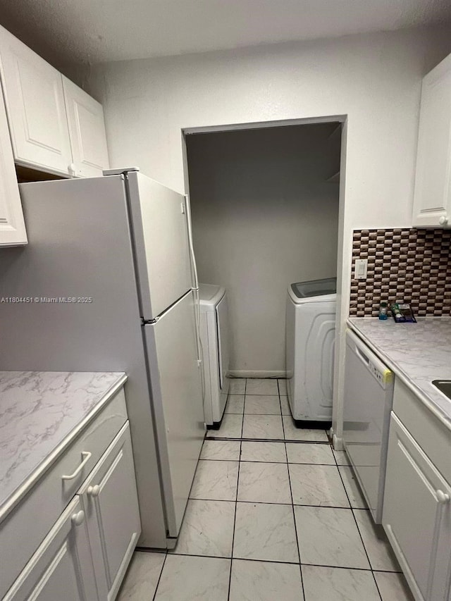 927 NE 199th St Unit 102, Miami, FL 33179 - kitchen featuring white appliances, washer / clothes dryer, light countertops, and light marble finish floors