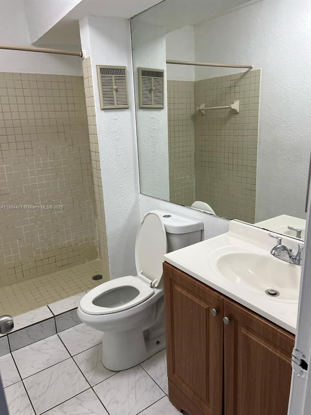 927 NE 199th St Unit 102, Miami, FL 33179 - full bathroom featuring a shower stall, toilet, a textured wall, marble look tile flooring, and vanity