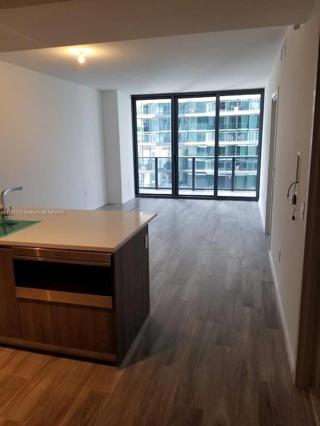 801 S Miami Ave Unit 1207, Miami, FL 33130 - kitchen with wood finished floors, a wall of windows, a sink, and light countertops