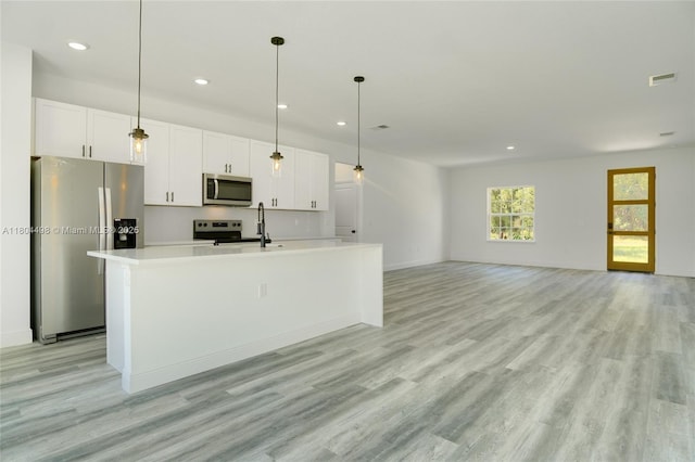 5998 SW 128th Street Rd, Ocala, FL 34473 - kitchen with stainless steel appliances, white cabinetry, a kitchen island with sink, recessed lighting, and light wood-style flooring